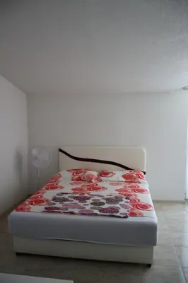 a bed with a red and white blanket on it at Villa Leamax - Stan 9 in Velika Kladuša