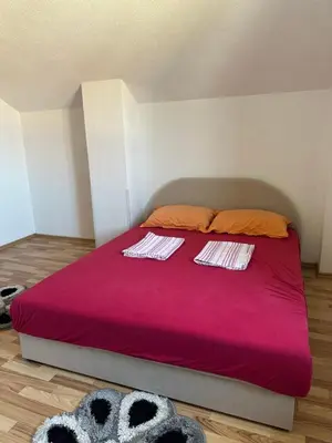 a bedroom with a red bed with two towels on it at Apartman Lida in Izačić