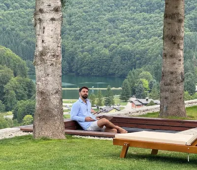 a man sitting on a bench next to two trees at Mountain House LISINSKA ROSA in Brdo