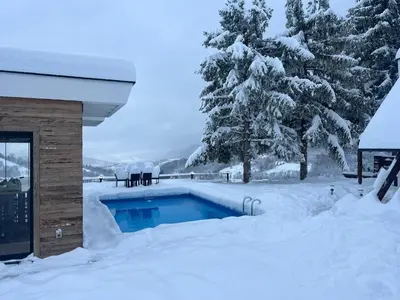 a swimming pool covered in snow next to a house at Mountain House LISINSKA ROSA in Brdo