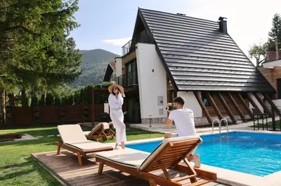 a man and woman standing next to a swimming pool at Mountain House LISINSKA ROSA in Brdo