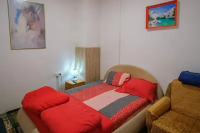 a small bedroom with a bed with a red blanket at Natural paradise Sake in Visoko