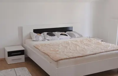 a white bedroom with a large white bed with a white headboard at Wildlight in Bihać