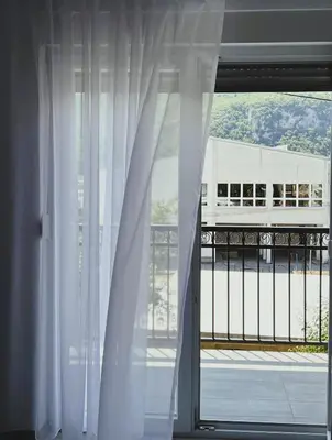 a window with white curtains and a view of a building at Apartman 369 in Jajce