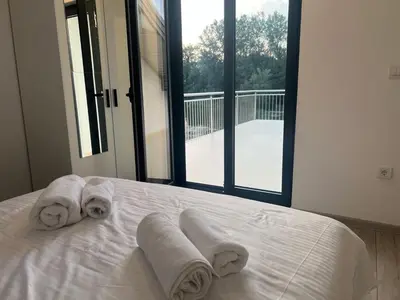 a bed with three towels on it with a window at Apartmani na Uni Šarac