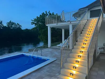 a house with a swimming pool and stairs next to a house at Apartmani na Uni Šarac