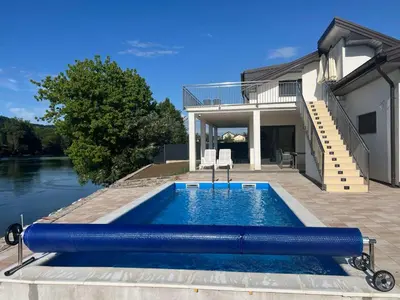 a swimming pool in front of a house at Apartmani na Uni Šarac