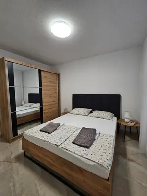 a bedroom with a large bed and a mirror at Apartman devet rijeka in Sanski most