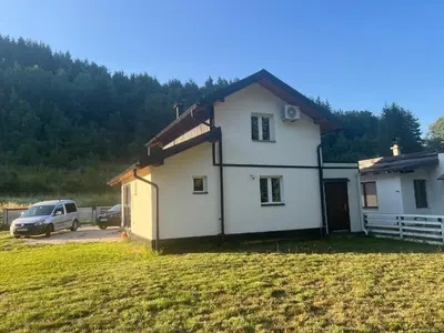a white house with a car parked in a field at Oaza mira -Trnovo in Ivišovo Greblje