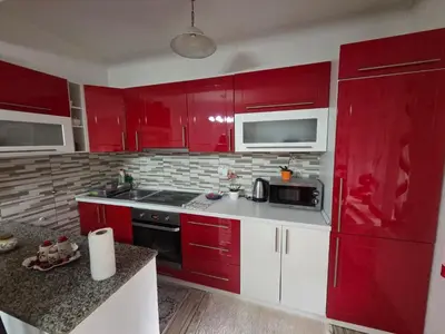a red kitchen with white cabinets and a microwave at Apartman Stan na dan Happy Family Bihać in Ribić
