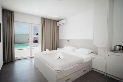 a white bedroom with a bed with towels on it at Villa Apartments Blanco - Near Airport Banja Luka in Laktaši