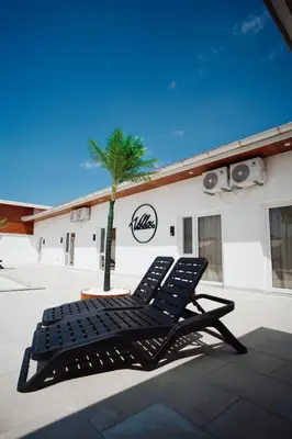 a pair of black lounge chairs next to a palm tree at Villa Apartments Blanco - Near Airport Banja Luka in Laktaši