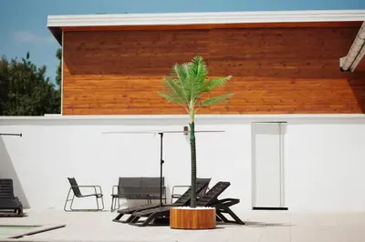 a palm tree on a patio with chairs at Villa Apartments Blanco - Near Airport Banja Luka in Laktaši