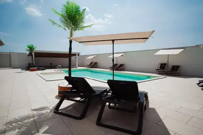 two chairs and an umbrella next to a swimming pool at Villa Apartments Blanco - Near Airport Banja Luka in Laktaši