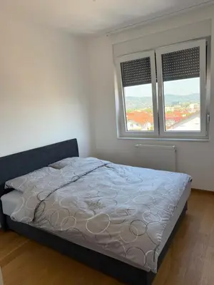a bedroom with a bed and two windows at Panorama apartman in Banja Luka