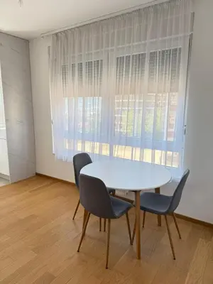 a white table and chairs in a room with a window at Panorama apartman in Banja Luka