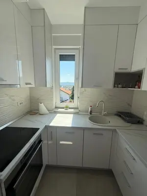 a white kitchen with a sink and a window at Panorama apartman in Banja Luka