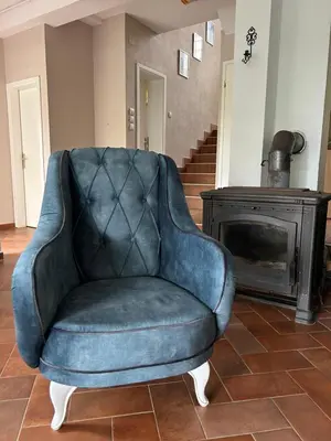 a blue chair sitting in a living room with a fireplace at Villa Ela in Prijedor