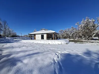 a snow covered yard with a house in the background at Villa Verde House by the River Sturba in Livno