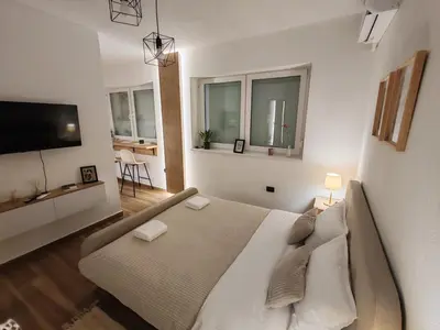 a large white bedroom with a bed and a flat screen tv at Studio 23 in Banja Luka