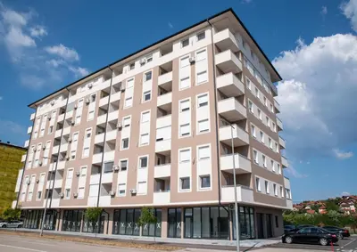 a large tan building on the side of a street at Apartman Sunset Doboj in Doboj