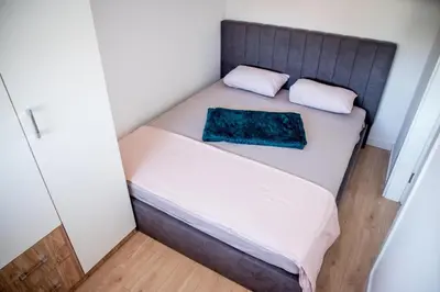 a small bed in a small room with a blue pillow at Apartman Sunset Doboj in Doboj