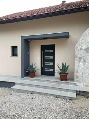 a house with a blue door and two potted plants at Kuća za odmor Ana in Zenica