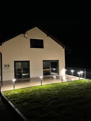 a white building with lights on the grass at night at Kuća za odmor Ana in Zenica