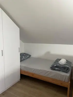 a bed in a room with a white wall at Kuća za odmor Ana in Zenica
