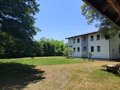 a white building with a grass yard and a bench at Al-Batten Vila Bihac in Bare