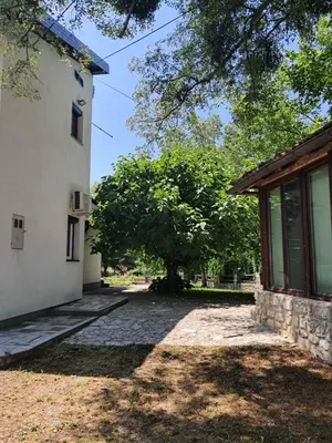 a house with a tree next to a building at Al-Batten Vila Bihac in Bare