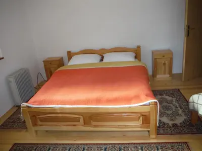 a bedroom with a wooden bed with an orange blanket at Holiday Home Villa Snježina in Vlasic