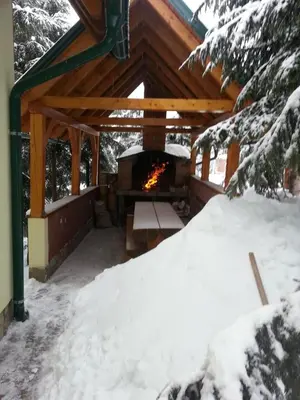 a covered deck with a fireplace in the snow at Holiday Home Villa Snježina in Vlasic