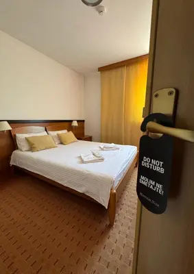 a hotel room with a bed with a sign on the door at Hotel Petar in Kotor-Varoš