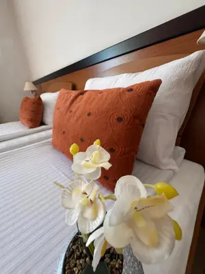 a bed with white flowers in a vase on it at Hotel Petar in Kotor-Varoš