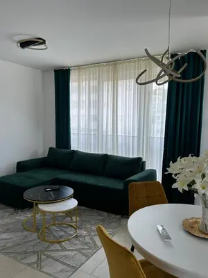 a living room with a green couch and a table at Lux Apartman Banjaluka in Banja Luka