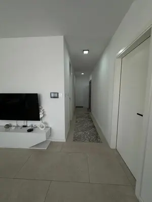 a hallway with a television on a white wall at Lux Apartman Banjaluka in Banja Luka