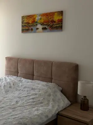 a bedroom with a bed and a painting on the wall at Lux Apartman Banjaluka in Banja Luka