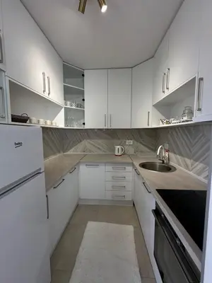 a white kitchen with white cabinets and a sink at Lux Apartman Banjaluka in Banja Luka