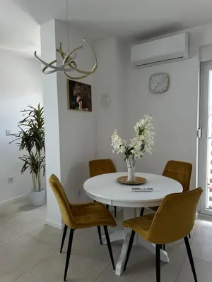 a white dining room with a white table and chairs at Lux Apartman Banjaluka in Banja Luka