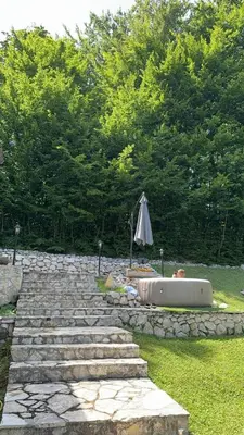 a stone path with an umbrella next to a bathtub at Rancbl in Banja Luka