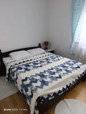 a bedroom with a bed with a blue and white quilt at Apartman Phoenix in Banja Luka