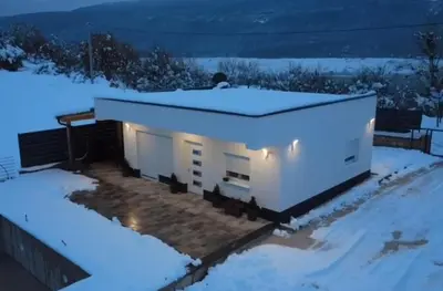 a small white building with lights in the snow at Kuća za odmor Ana in Prozor