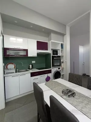 a kitchen with white cabinets and a table with chairs at Una Festa Apartment in Bihać