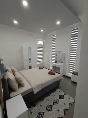 a white bedroom with a large bed and a rug at Una Festa Apartment in Bihać