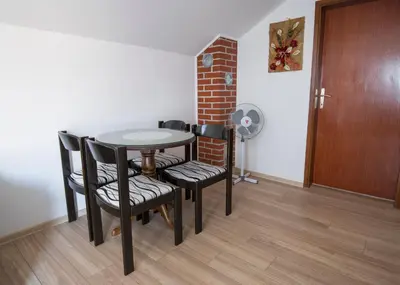 a dining room with a table and chairs and a brick wall at Apartment Anastasija in Doboj