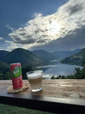 a glass of milk on a table with a view of a lake at Cottage Arinda in Jajce