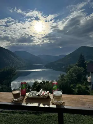 a table with a plate of food and a view of a lake at Cottage Arinda in Jajce