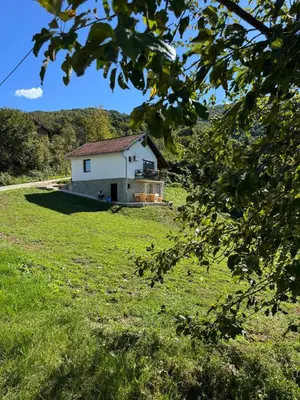 a small white house in a field of grass at Cottage Arinda in Jajce