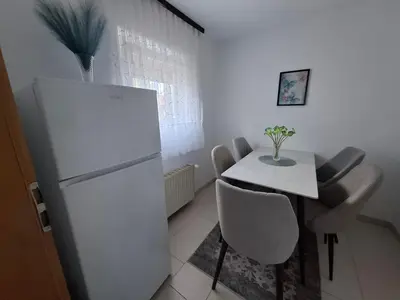a kitchen with a white refrigerator and a table and chairs at Apartman Mint in Bihać